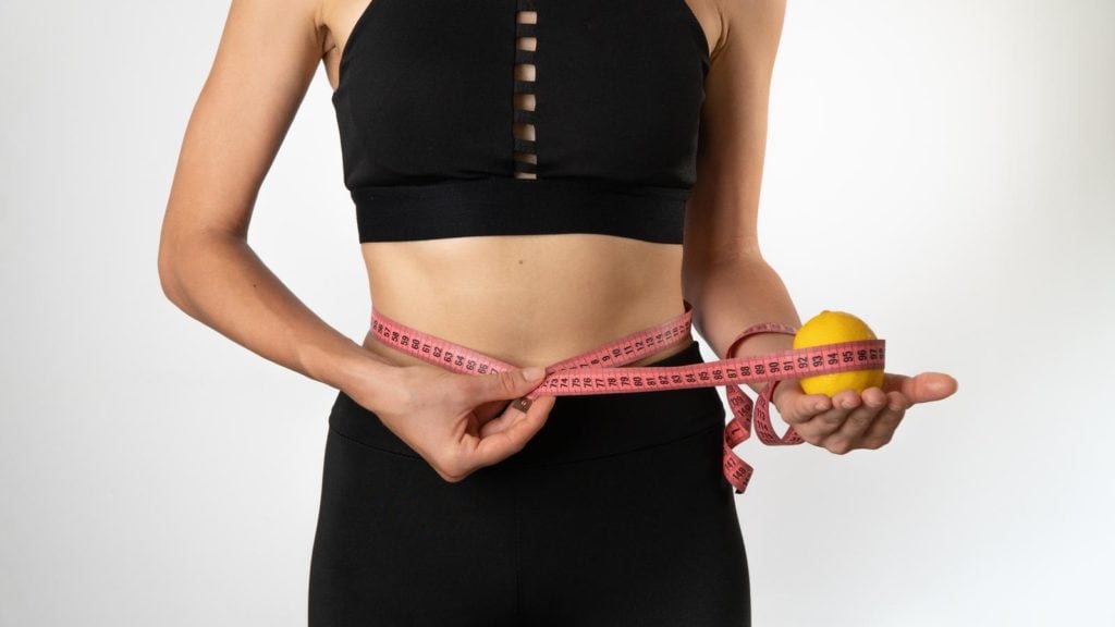 A Woman Measures The Figure With A Ribbon, A Lemon In Her Hand Weight Loss, Healthy Eating And Sports